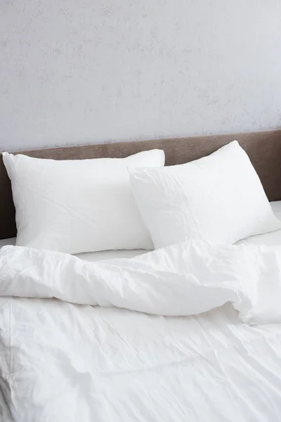 Hyggelig seng med sammenkrøllet hvidt linned - Stock-foto