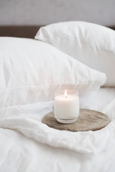 Палаюча свічка на дерев'яному підносі на білому натуральному полотні — стокове фото