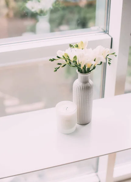 Buquê de freesias brancas em vaso e vela aromática na mesa — Fotografia de Stock