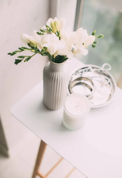 Bouquet di fresie bianche in vaso e candela aromatica sul tavolo — Foto Stock