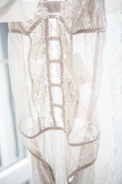 Elegant lacy lingerie on hanger in backlight, lace clothes detal — Stock Photo, Image