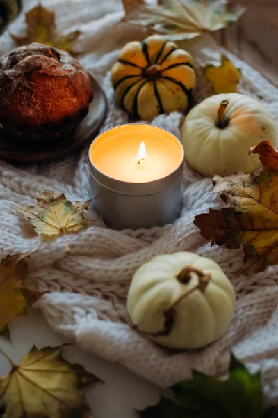 Burning candle in jar, autumn leaves and small decorative pumpki