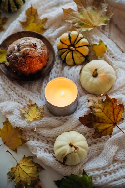 Burning candle in jar, autumn leaves and small decorative pumpki