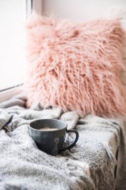 Fincan kahve, örme battaniye ve kuştüyü yastık üzerinde rahat pencere