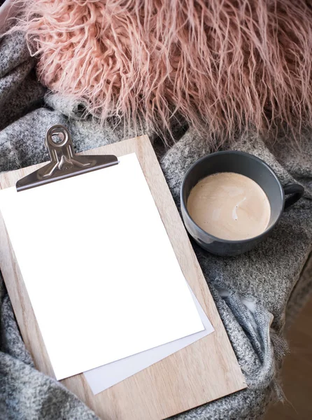 Cozy home arrangement with coffee cup and blank clipboard mockup