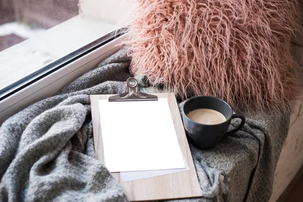 Cozy home arrangement with coffee cup and blank clipboard mockup