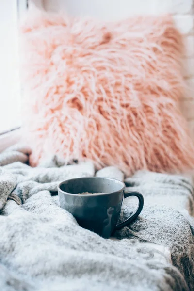 Чашка кофе, трикотажное одеяло и пушистая подушка на уютном подоконнике — стоковое фото