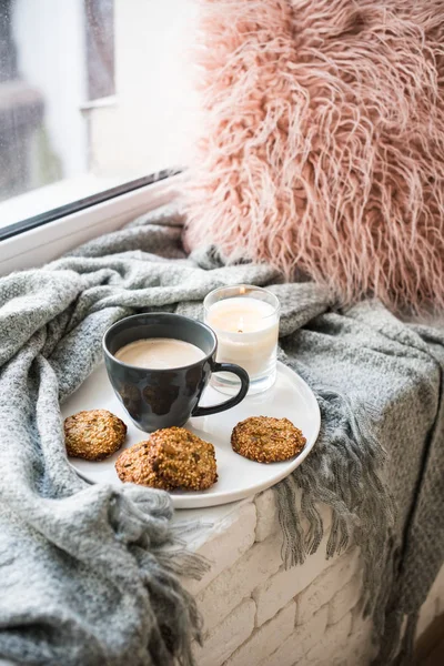 Scandinavische stijl ontbijt, kopje koffie en koekjes op gezellige vensterbank met warme deken en kussen — Stockfoto