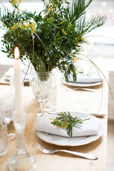 Gyönyörű tavasz táblázatot, amely a zöld levelek és a mimóza-ágakat, a fényes fehér asztal vacsora dekoráció — Stock Fotó