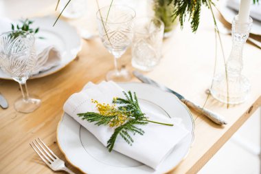 Güzel bahar sofra yeşil yaprakları ve mimoza dalları, parlak beyaz masa akşam yemeği dekorasyonu ile