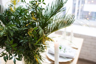 Güzel bahar sofra yeşil yaprakları ve mimoza dalları, parlak beyaz masa akşam yemeği dekorasyonu ile