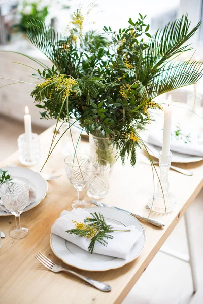 Hermosa mesa de primavera con hojas verdes y ramas mimosas, decoración de mesa blanca brillante — Foto de Stock