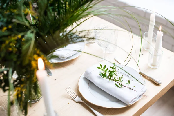 Beautiful springtime table setting with green leaves and mimosa branches, bright white table dinner decoration — Stock Photo, Image