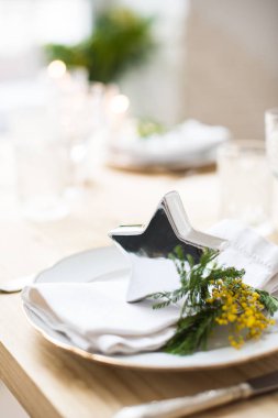 Güzel bahar sofra yeşil yaprakları ve mimoza dalları, parlak beyaz masa akşam yemeği dekorasyonu ile