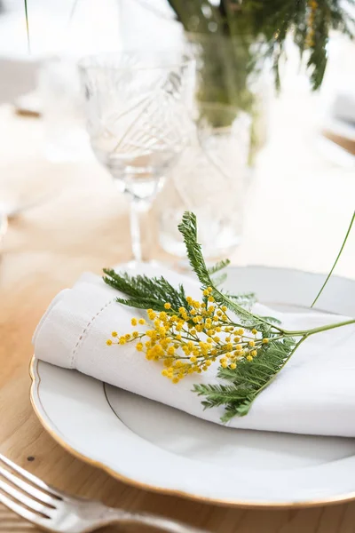 Bonita tabela de primavera com folhas verdes e ramos mimosa, decoração de jantar mesa branca brilhante — Fotografia de Stock