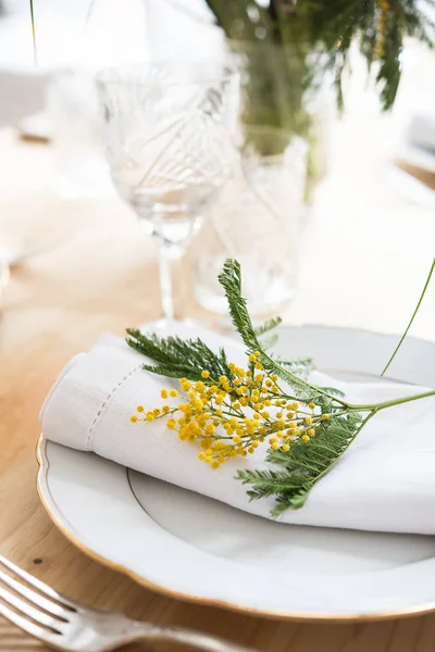 Beau cadre de table de printemps avec des feuilles vertes et des branches de mimosa, décoration de dîner de table blanche lumineuse — Photo