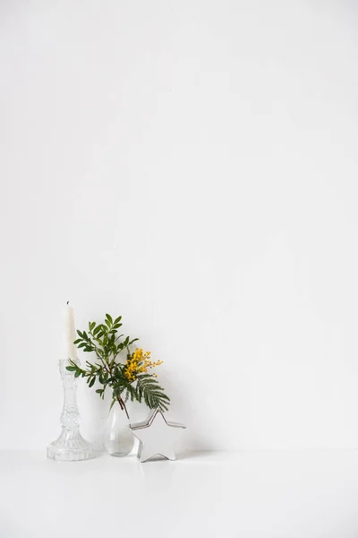 Small bouquet with green leaves and mimosa flowers and empty white wall — Stock Photo, Image