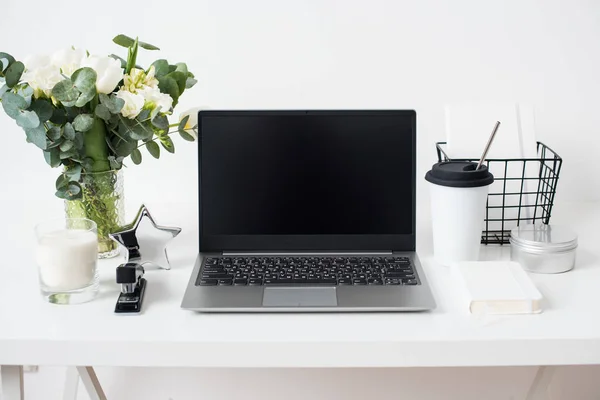 Hipster bloggare arbetsplats, laptop och blommor på vit bordsskiva — Stockfoto