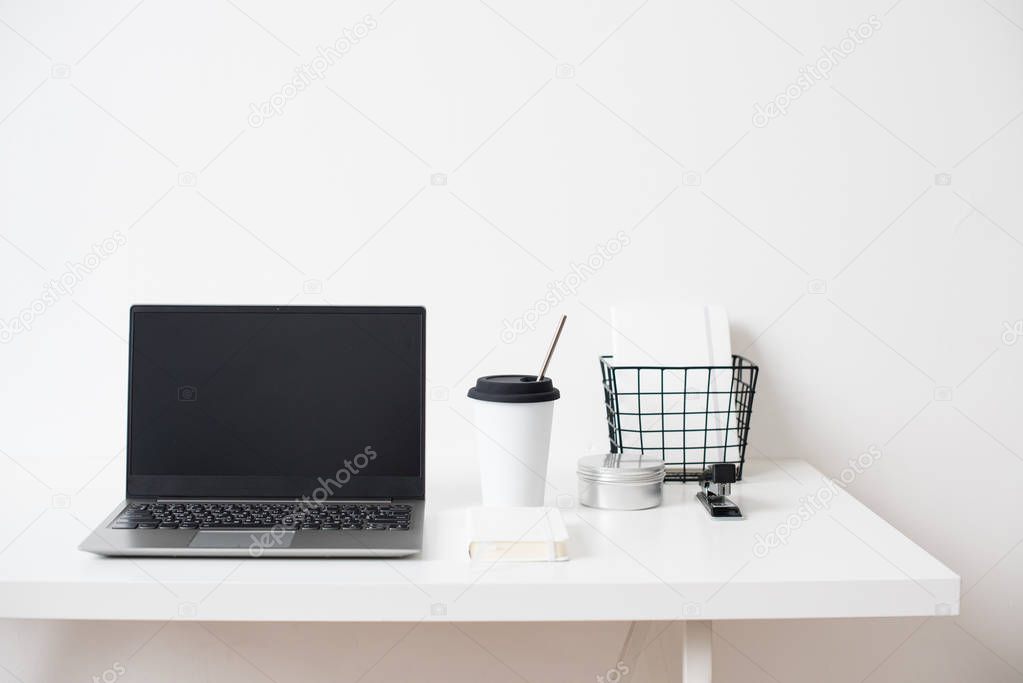 Hipster bloggers work place, laptop and flowers on white tabletop