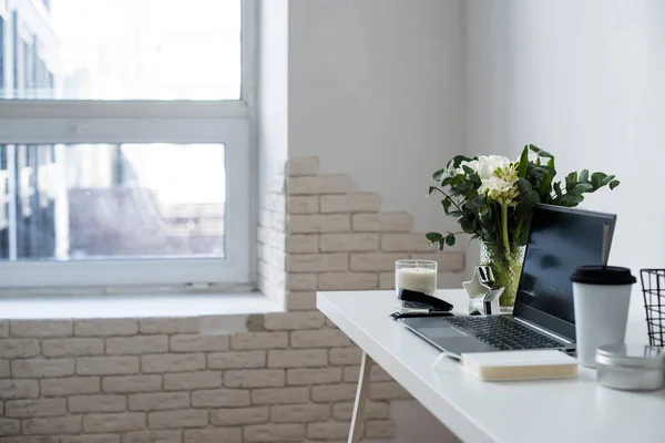 Hipster bloggers werkplek, laptop en bloemen op wit tafelblad — Stockfoto