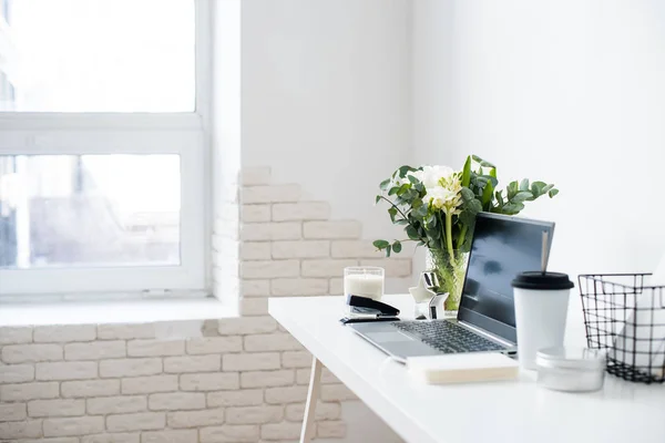 Hipster bloggers werkplek, laptop en bloemen op wit tafelblad — Stockfoto