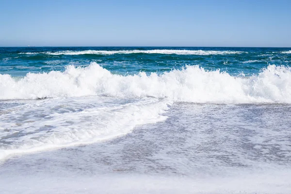 Zee golven op het strand, helder blauw water — Stockfoto