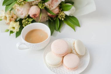 Zarif tatlı tatlı macarons, kahve ve pastel renkli bej çiçekler Buket fincan