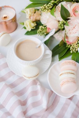 Zarif tatlı tatlı macarons, kahve ve pastel renkli bej çiçekler Buket fincan