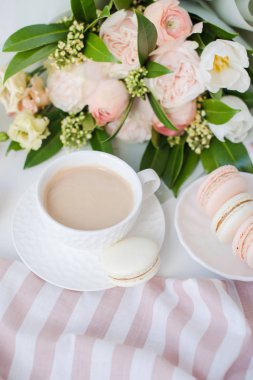 Zarif tatlı tatlı macarons, kahve ve pastel renkli bej çiçekler Buket fincan