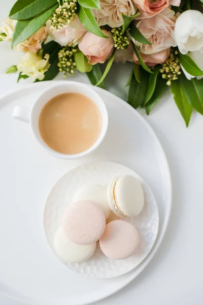 Elegancki słodki makarony deser, filiżanka kawy i pastelowy kolor beżowy kwiaty bukiet — Zdjęcie stockowe
