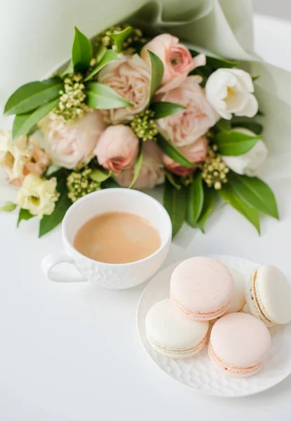 Elegancki słodki makarony deser, filiżanka kawy i pastelowy kolor beżowy kwiaty bukiet — Zdjęcie stockowe