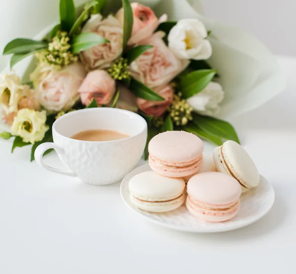 Macarons de sobremesa doce elegante, xícara de café e pastel colorido buquê de flores bege — Fotografia de Stock