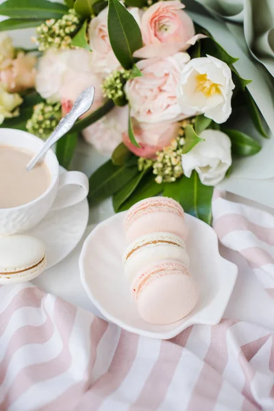 Zarif tatlı tatlı macarons, kahve ve pastel renkli bej çiçekler Buket fincan — Stok fotoğraf