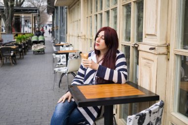 Uzun saçlı genç bayan dondurma yiyor.