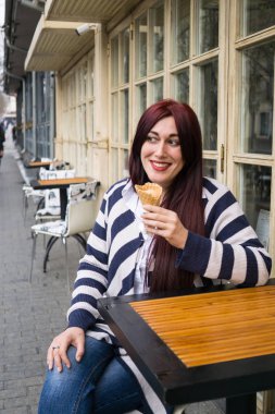 Uzun saçlı genç bayan dondurma yiyor.