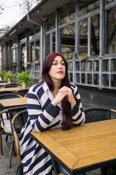 Giovane signora con i capelli lunghi seduta da sola nel caffè — Foto Stock