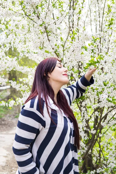 Mujer hermosa joven con ramas de árbol florecientes — Foto de Stock