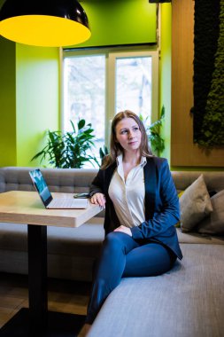 Şehir merkezindeki kafede dizüstü bilgisayarla çalışan genç bir iş kadını.