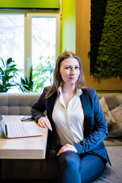 Young business woman working with laptop on the table in the city cafe interior — Stock Photo, Image