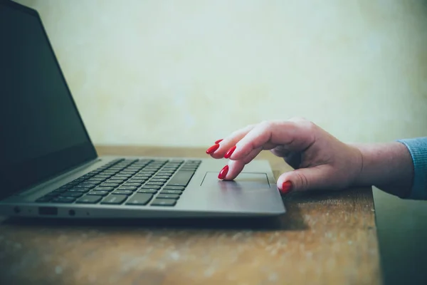 Womans hand with red nails on laptop keyboard, lady using laptop on old vintage table