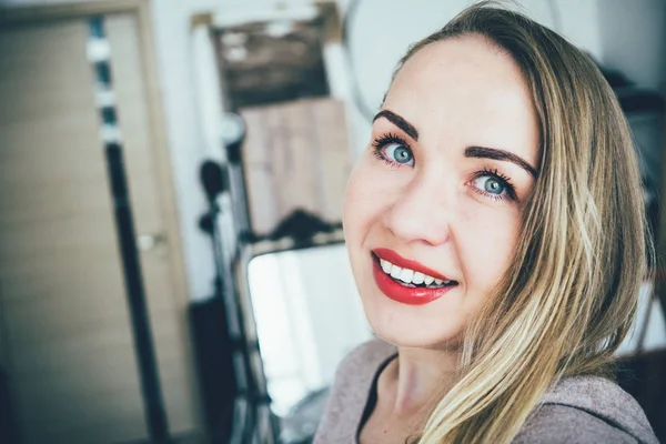 Gülümseyen genç Avrupalı sarışın kadın stüdyo dairesinde selfie yapıyor — Stok fotoğraf