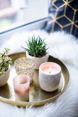 Rahat gerçek ev dekorasyonu, pencere üzerinde beyaz sahte kürk yastık ile altın tepside mumlar yanan