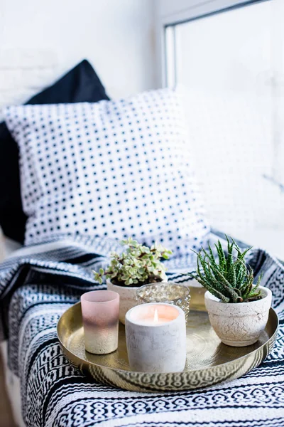 Echte Wohnungseinrichtung, aromatische Kerzen und Pflanzen auf Vintage-Tablett mit Kissen und Decke auf weißem Fensterbrett — Stockfoto