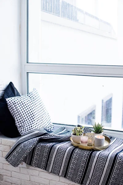 Vero appartamento arredamento d'interni, candele aromatiche e piante su vassoio d'epoca con cuscini e coperta sul davanzale bianco — Foto Stock