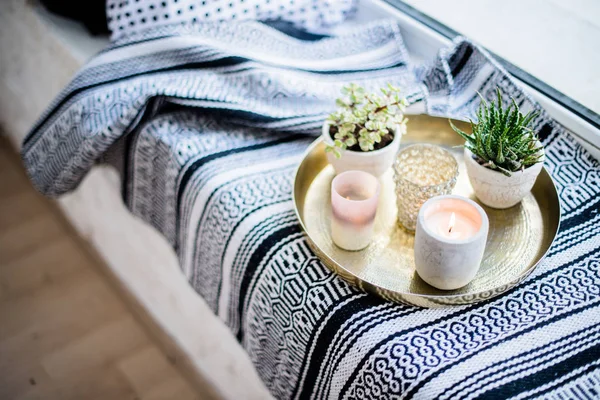 Echte Wohnungseinrichtung, aromatische Kerzen und Pflanzen auf Vintage-Tablett mit Kissen und Decke auf weißem Fensterbrett — Stockfoto