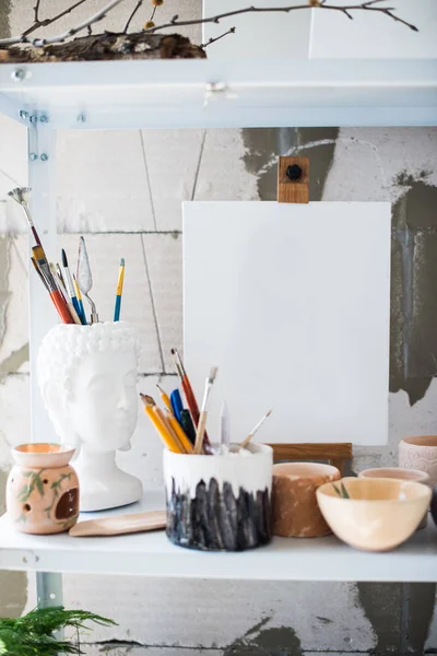 Pencils, canvas and brushes on shelf in artistic studio — Stock Photo, Image