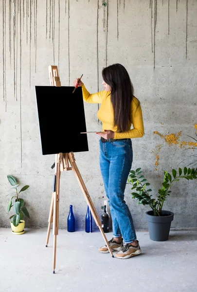 Young lady painter artist with isolated canvas artwork mock-up on easel — 스톡 사진