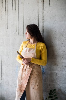 Çatı katında boya lekeleri olan önlüklü genç ve güzel bir bayan sanatçı.