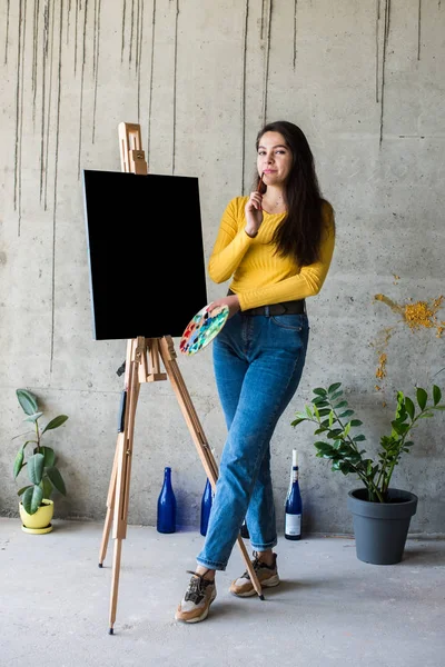 Young lady painter artist with isolated canvas artwork mock-up on easel — Stock Photo, Image