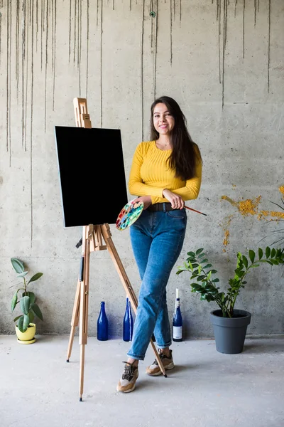 Young lady painter artist with isolated canvas artwork mock-up on easel — 스톡 사진